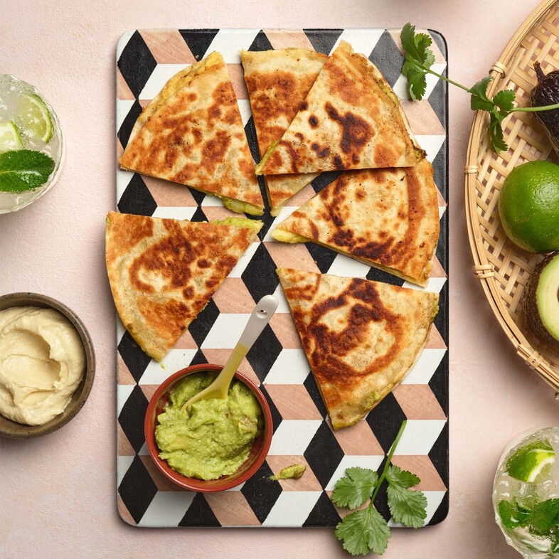 Quesadillas fyllda med hummus, guacamole och smält ost, gyllenbruna och skurna i mindre bitar för servering.