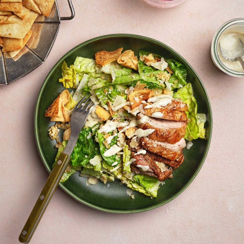 Caesarsallad med saftig kyckling, krispig romansallad, fullkornsbulgur och vitlökskrutonger, toppad med parmesan.